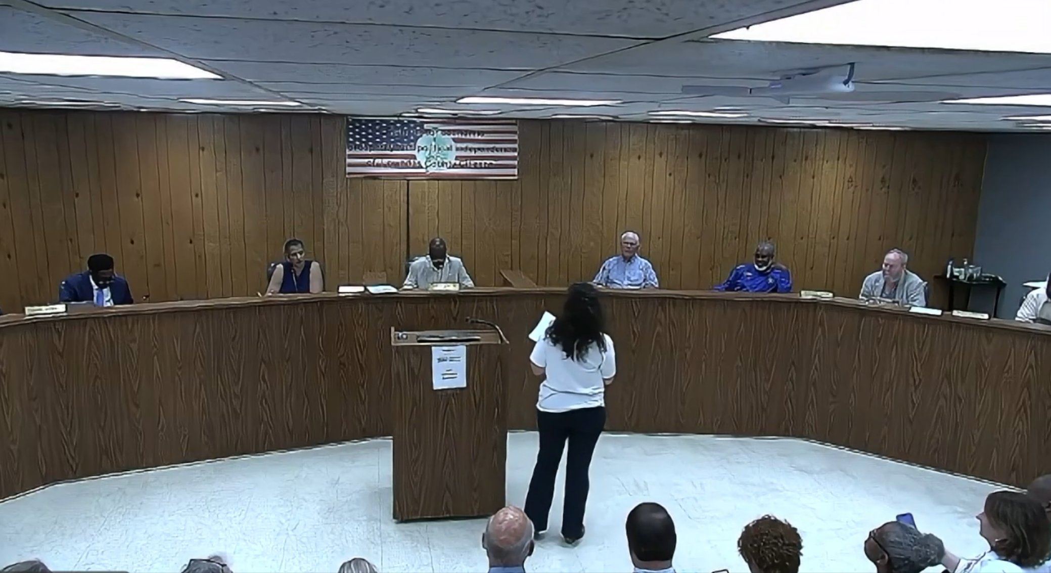 A resident, seen from behind, addresses the Lowndes County Commission from the podium during the May 26, 2026 meeting, with commissioners seated at the dais.