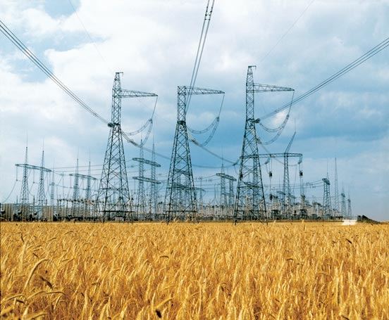 High-voltage electrical transmission lines and towers against the sky.